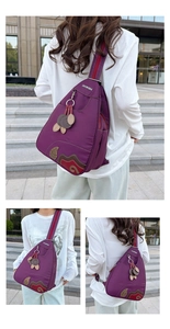 Detail of purple waterproof nylon bag with colorful embroidered patches and leaf charm