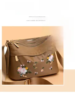 Detail of khaki nylon shoulder bag with floral embroidery and triple metal zippers