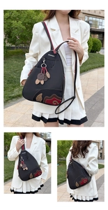Detail of waterproof Oxford backpack showing contrast leaf embroidery and leather charm