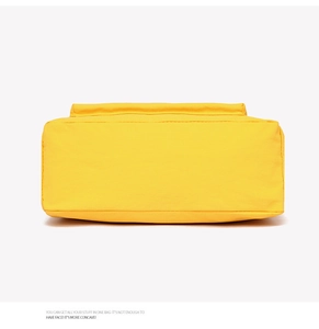 Detailed view of the wide rectangular bottom and stitching of the yellow canvas tote bag