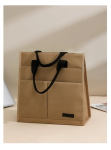Close-up of khaki canvas tote with multi-pocket design and black woven handles