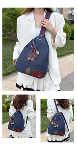 Detail of navy blue waterproof nylon backpack with floral embroidery and cherry charm