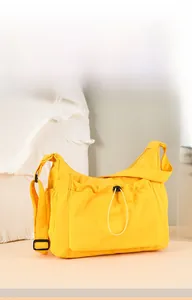 Detail of yellow canvas tote bag with front drawstring pocket and adjustable black strap
