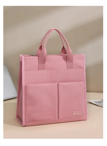 Close-up of pink canvas office tote featuring multiple pockets and metal zipper detail