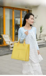 Outdoor shot of bright yellow canvas tote bag with dual front pockets and top handles