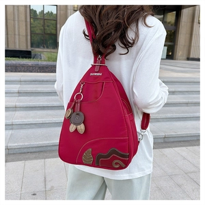 Outdoor shot of a waterproof nylon rose red backpack with leaf pattern and metal logo