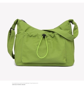Detail view of grass green canvas tote bag showing front drawstring pocket and zipper