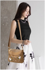 Detail of khakic nylon crossbody bag with floral embroidery and triple zipper layers