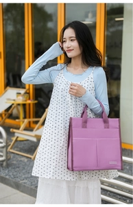 Detail of a purple canvas tote bag with front pockets and sturdy fabric handles