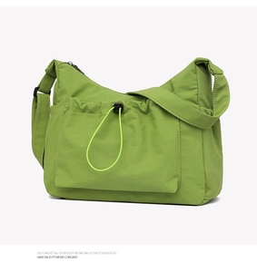 Detail of bright green nylon hobo bag featuring adjustable drawstring front pocket