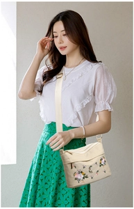 Detailed embroidery of colorful flowers on a beige nylon crossbody bag with wide strap