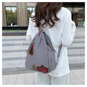 Detailed back view of grey waterproof oxford backpack with leaf embroidery and red zippers