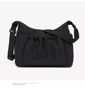 Detail of black nylon crossbody bag featuring drawstring pocket and adjustable shoulder strap