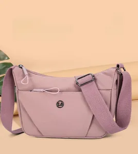 Détails de la bandoulière réglable et logo en métal sur un sac à bandoulière en nylon rose