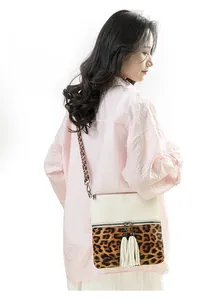 Détail du sac bandoulière en cuir PU avec coutures léopard et zips à pompons blancs