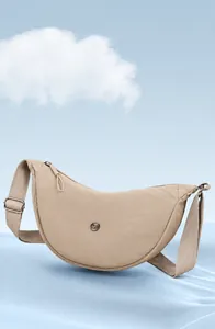 Dettaglio borsa a mezzaluna in nylon beige con tracolla regolabile e logo metallico