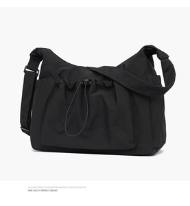 Detail of the black canvas tote bag showing the front drawstring pocket and toggle closure