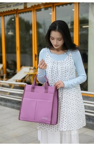 Outdoor lifestyle shot of a purple canvas tote bag with functional front pockets and trim