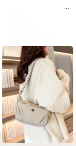 Détail d'un sac bandoulière en nylon beige avec logo métallique rond et sangle réglable