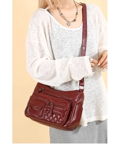 Détail du sac bandoulière bordeaux avec poches matelassées et texture en cuir souple