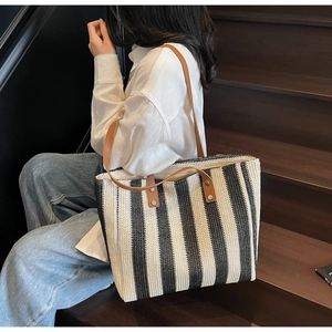 Detail of handwoven tote bag with vertical stripes and brown leather shoulder straps