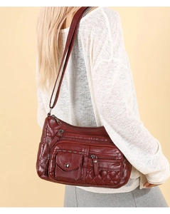 Détail du sac bandoulière en cuir souple bordeaux avec fermetures éclair et rivets
