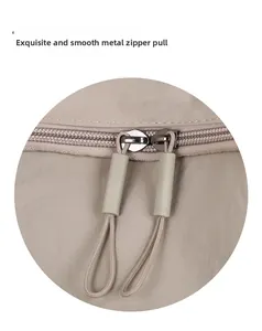 Detail of smooth metal double zippers with durable matte cords on a beige nylon backpack