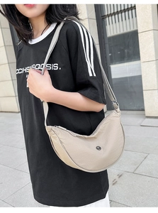 Dettaglio tracolla regolabile e zip su borsa a mezzaluna in nylon beige chiaro