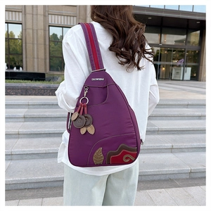 Detail of purple waterproof nylon chest bag with leaf embroidery and metallic logo plate