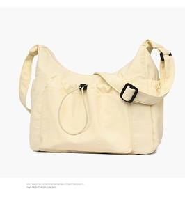 Detail of cream canvas tote bag showing drawstring front pocket and adjustable strap