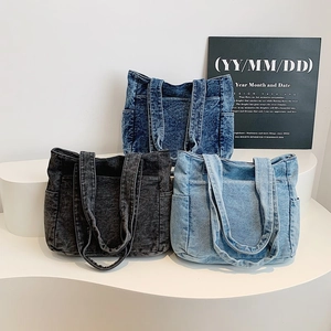 Three denim tote bags in dark blue, black grey, and light blue on display stands