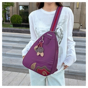 Detail of purple nylon crossbody chest bag with ethnic leather applique and floral charm