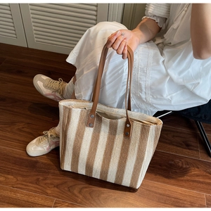 Detailed texture of vertical striped woven tote bag with brown faux leather shoulder straps