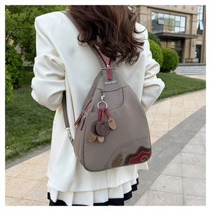 Detail of waterproof oxford backpack with leaf embroidery and leather pendant on zipper