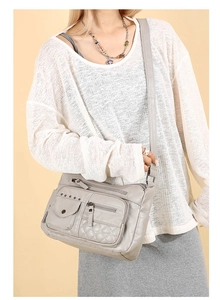 Sac bandoulière gris multi-poches avec détails matelassés et bandoulière réglable sur mannequin