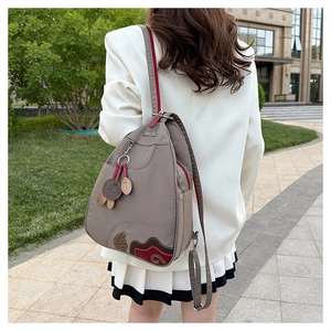 Detail of grey waterproof nylon backpack with floral patchwork embroidery on model