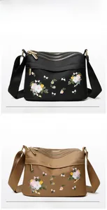 Detail view of black and brown embroidered nylon bags with three zipper compartments