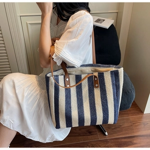 Detail of navy and white striped woven tote with brown leather handles and rivets