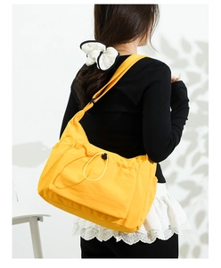 Detailed view of yellow canvas tote bag with adjustable strap and drawstring front pocket