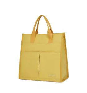 Side view of yellow canvas laptop tote bag with reinforced edges and front pockets