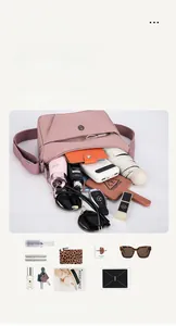 Détail montrant la grande capacité d'un sac bandoulière en nylon rose avec objets du quotidien