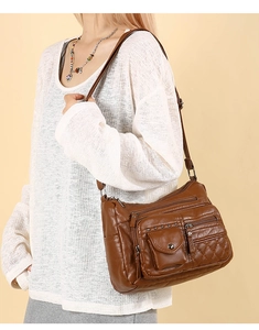 Détail d'un sac bandoulière marron en similicuir avec poches zippées et texture matelassée