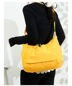 Detail of yellow drawstring canvas tote bag showing the side pocket and shoulder strap