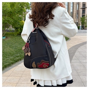 Waterproof black nylon backpack with leaf embroidery shown on a model in an outdoor setting