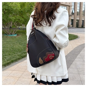 Detail of waterproof black nylon crossbody bag with ethnic patchwork on a street model