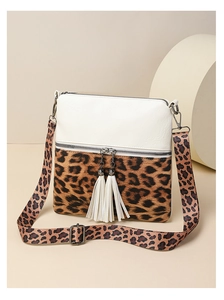 Détail du sac bandoulière léopard bicolore avec pompons blancs et finitions dorées