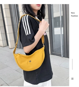 Vista laterale di una borsa a tracolla a mezzaluna in nylon giallo brillante indossata da una modella