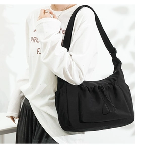 Detail view of black canvas crossbody bag with drawstring pocket and adjustable wide strap