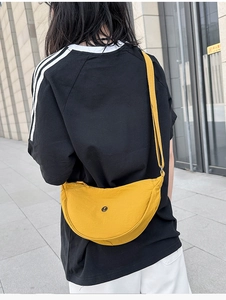 Dettaglio della borsa a mezzaluna in nylon giallo con tracolla e logo nero