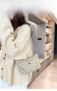 Détail d'un sac bandoulière en nylon beige avec sangle réglable et logo sur un modèle